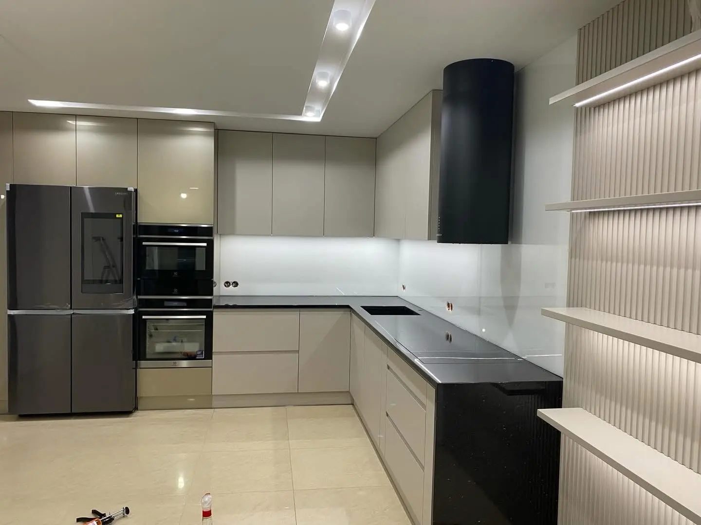 Greige U-shaped kitchen with black countertop and hood