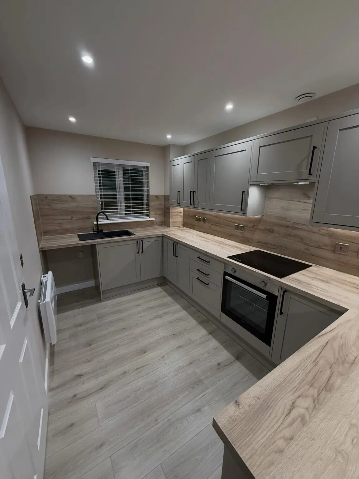 Gloss white kitchen with black worktop and marble-pattern backsplash