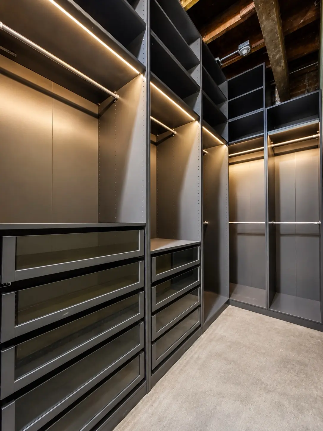 Dark walk-in closet with open drawers and LED lighting